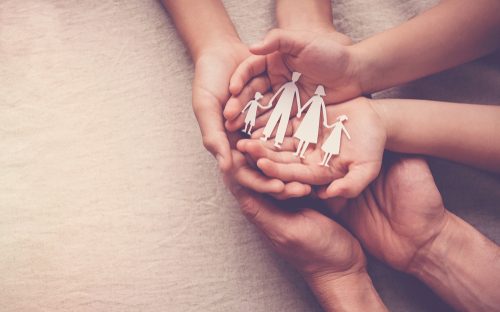 family with their hands put together holding a paper cut family