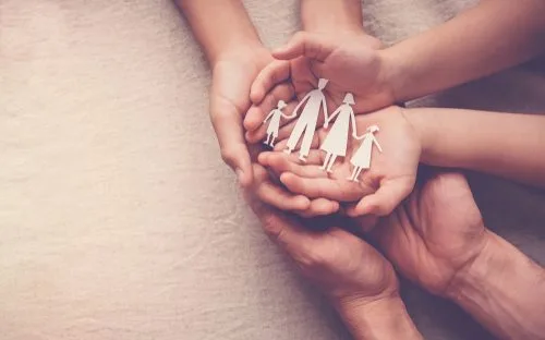 family with their hands put together holding a paper cut family